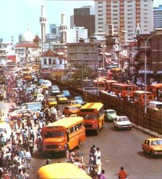 a busy city street filled with lots of traffic and people walking on the side of it