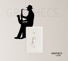 a wall mounted light switch plate with a silhouette of a man playing the saxophone