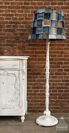 a white table with a lamp on it next to a brick wall and an old dresser