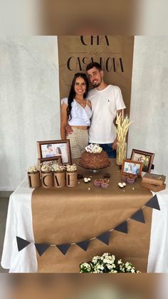 a man and woman standing in front of a table with food on it, posing for a photo