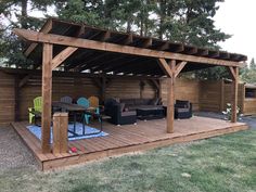 a wooden deck with chairs and table next to a covered outdoor living area in the back yard