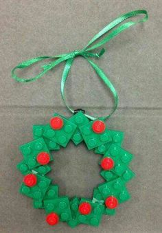 a christmas ornament made out of legos on a gray surface with a green ribbon