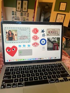 an open laptop computer sitting on top of a bed covered in pictures and magnets