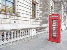 a red phone booth sitting on the side of a building