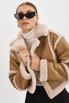 Introducing the Mariane Detachable Faux Shearling Coat, a versatile outerwear piece that offers a range of styling options. With its faux shearling trim and snap button detachable hem at the waist, this coat allows you to switch between a long coat and a cute cropped jacket. Chic Brown Shearling Outerwear, Chic Shearling Fur Coat For Cold Weather, Beige Sherpa Outerwear With Faux Fur Lining, Chic Shearling Outerwear For Fall, Beige Sheepskin Outerwear For Cold Weather, Chic Sheepskin Outerwear With Faux Fur Trim, Chic Beige Outerwear With Faux Fur Lining, Beige Shearling Outerwear With Faux Fur Lining, Beige Shearling Outerwear For Cold Weather