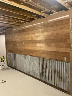 an unfinished room with wood paneling on the walls and metal pipes running through it