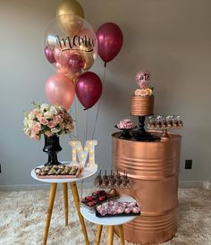 a table topped with lots of desserts and balloons next to a large metal barrel