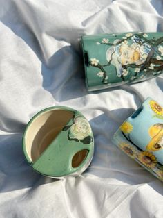 three ceramic vases sitting on top of a white cloth covered bed spread with sheets