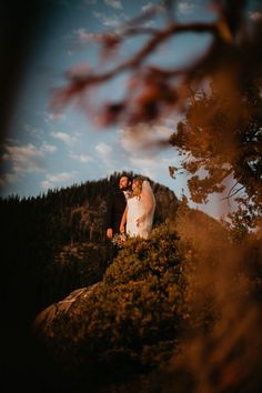 a bride and groom standing on top of a mountain