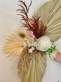 an arrangement of dried flowers and grasses on a wall