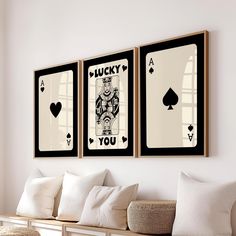 two framed playing cards hang on the wall above a bench with pillows and throw pillows