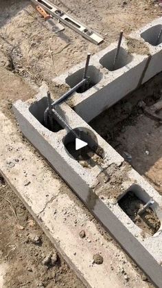 concrete blocks with holes in the middle and tools laying around them on top of dirt