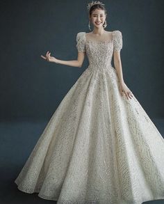 a woman in a white dress posing for the camera with her hand out and wearing a tiara