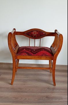 a wooden chair sitting on top of a hard wood floor next to a white wall