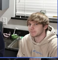 two young men sitting next to each other in a kitchen