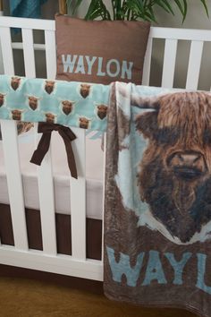 a baby crib with a brown and blue blanket next to a white crib