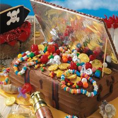 a pirate chest cake with lots of candy and coins on the table next to it