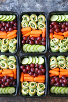 several trays filled with cucumbers, grapes, and other veggies