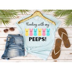 "The perfect Easter shirt for any book lover! This cute T-shirt features the phrase \"Reading with my Peeps!\" along with illustrations of yummy bunny peeps. This classic unisex jersey short-sleeve tee fits like a well-loved favorite. Soft cotton and quality print make users fall in love with it over and over again. These t-shirts have ribbed knit collars to bolster shaping. The shoulders have taping for a better fit over time. Dual side seams hold the garment's shape for longer.  .: 100% Airlum Spring Bookish T-shirt With Letter Print, Bunny Peeps, Teacher Tee Shirts, Teacher Tees, Easter Shirt, Cute Tshirts, Any Book, Librarian, Easter Gift