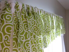 green and white curtains hanging on the side of a window