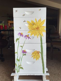 a painted dresser with yellow flowers and bees on it