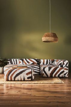 a zebra print couch sitting on top of a hard wood floor next to a potted plant