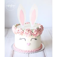 a white cake with pink frosting and bunny ears on top