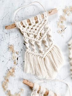 the macrame wall hanging is made with cotton yarn and wooden dows, along with two small pieces of wood