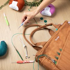 a person is holding a crochet hook in front of some knitting supplies on a table