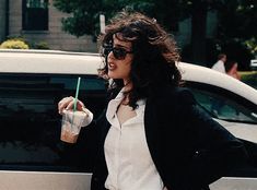 a woman is walking down the street with a drink in her hand