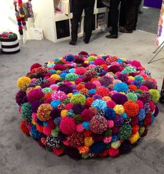 a colorfully decorated round object on the floor at an art show with people standing around it