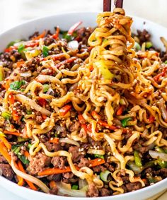 a bowl filled with noodles, meat and veggies on top of a table