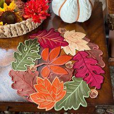 a wooden table topped with lots of different colored leaves and pumpkins on top of it