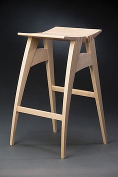 a wooden stool sitting on top of a gray floor