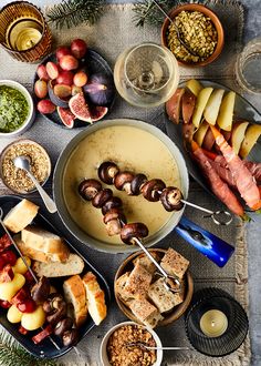 an assortment of meats and vegetables on a platter with olives, apples, bread