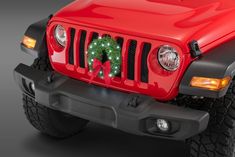 a red jeep with a christmas wreath on the front grill and lights in the back