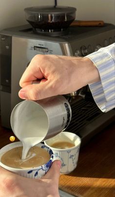 a person pouring something into a cup on top of a table