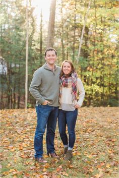 an engaged couple standing in the leaves