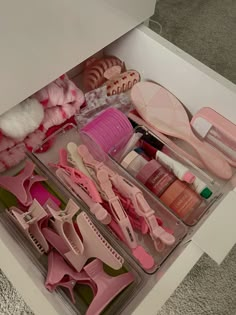 an open drawer filled with lots of pink items and hair accessories on top of carpeted flooring