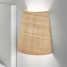 a lamp that is on the wall next to a light fixture with a fabric shade