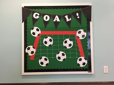 a soccer themed party sign hanging on the wall with balls and pennants in front of it