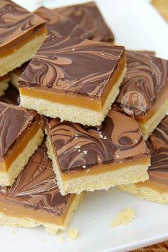 there are many pieces of chocolate and peanut butter bars on the plate, ready to be eaten