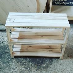 a wooden bench sitting on top of a cement floor next to a pile of wood