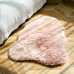 a pink sheepskin rug on the floor next to a bed