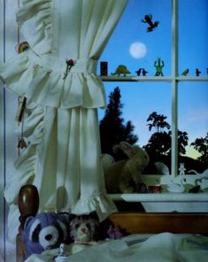 two stuffed animals sitting in front of a window with the curtains pulled back and drapes open