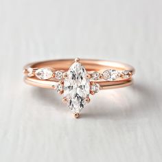 a rose gold engagement ring with an oval cut diamond in the center and side stones on each band