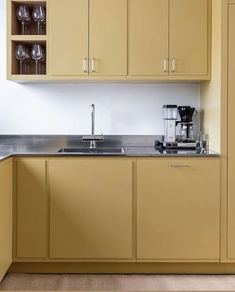 a kitchen with yellow cabinets and stainless steel counter tops, including a coffee maker on the left