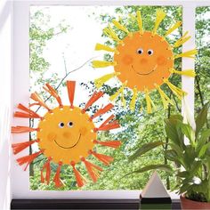 two paper sunflowers sitting on top of a window sill next to a potted plant