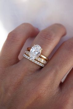 a woman's hand with two gold rings and a diamond ring on her finger