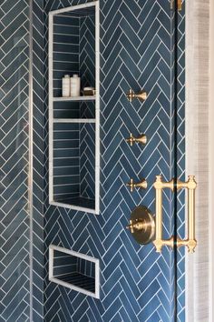 a bathroom with blue tile and gold fixtures on the shower wall, along with shelving